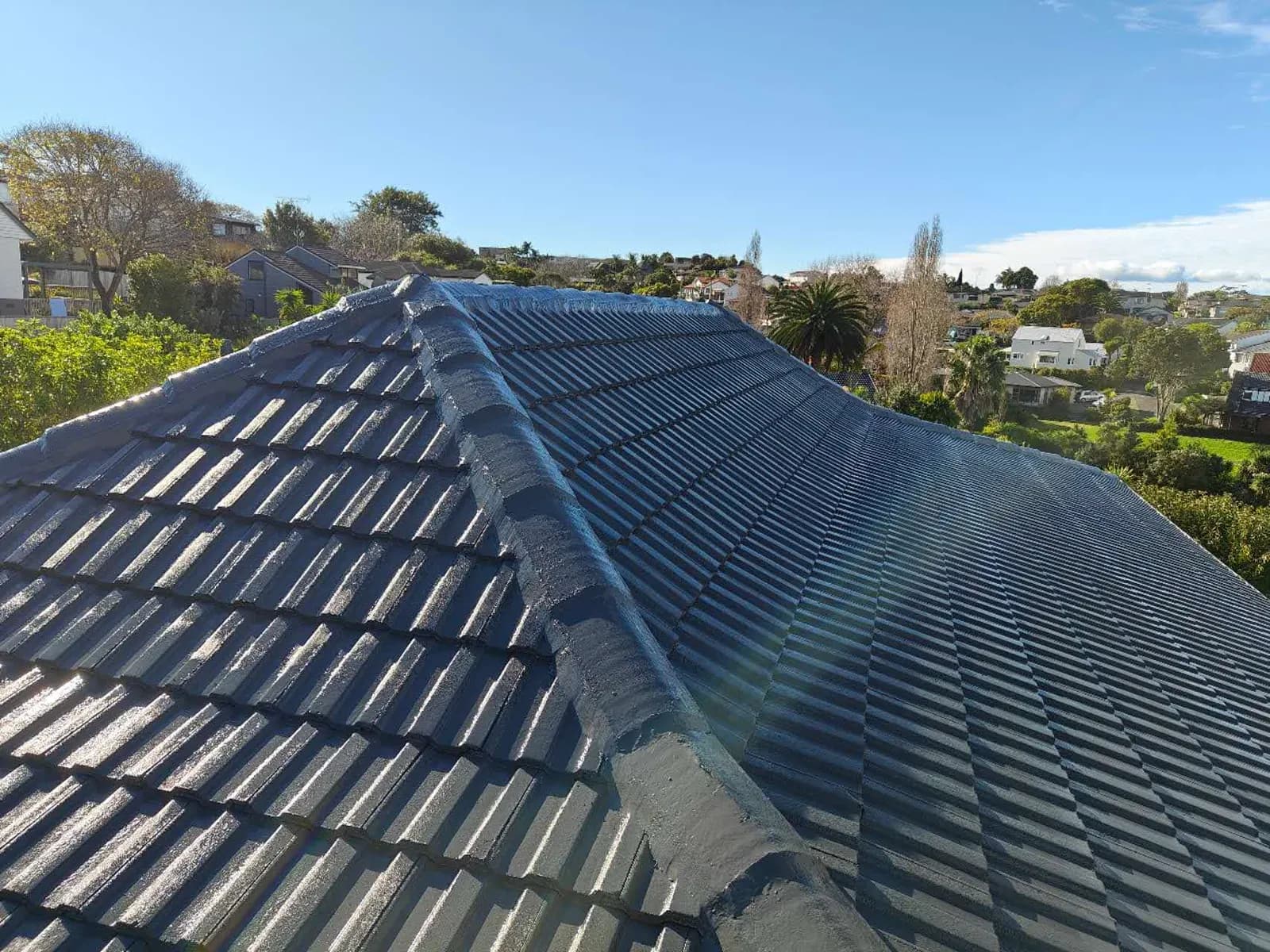 Auckland concrete tile roof ridge after recoating — even, deep colour and clean finish with sea view